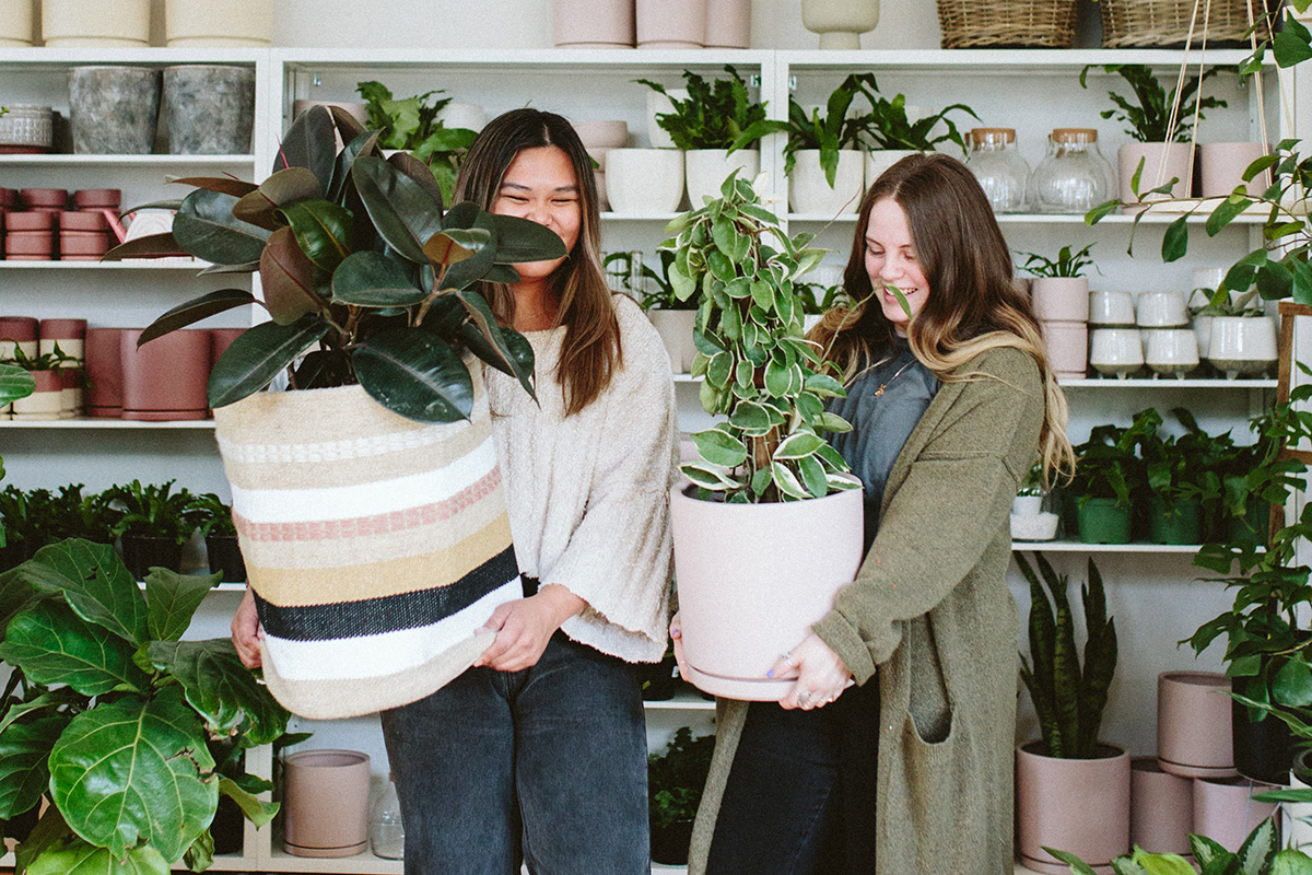 two plant shop workers holding plants