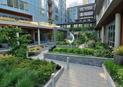 Apartment courtyard patio with lush plantings, sculpture, and trees by Dennis' 7 Dees